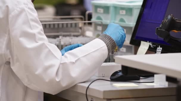 Naukowiec Białym Fartuchu Laboratoryjnym Niebieskich Rękawiczkach Analizuje Próbkę Przed Biurkiem — Wideo stockowe