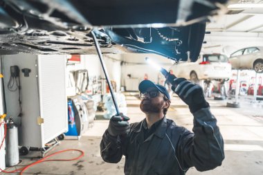 Photo of a mechanic checking cars undercarriage. Repair shop concept. High quality photo