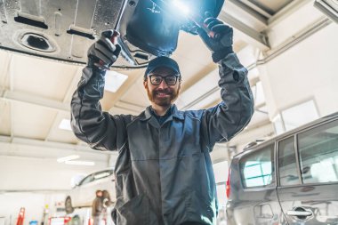 Medium low angle shot of a mechanic mid-work. Posing for a photo. Repair shop concept. High quality photo