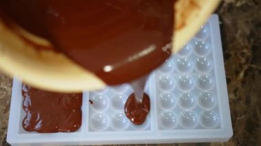 Top-down view of melted chocolate poured into sphere-shaped chocolate bar molds. Chocolate production process. Horizontal indoor video. High quality 4k footage