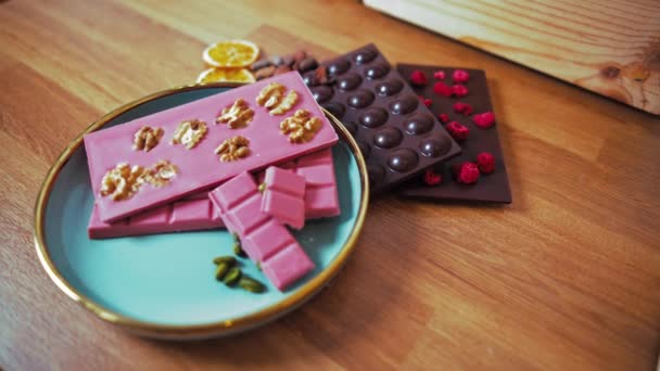 Pink Chocolate Bar Walnuts Pistachios Blue Gold Plate Dark Chocolate — Vídeos de Stock