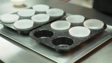 Baker puting paper cupcake liners on grey cupcake pan. Inside. Extrime close up. High quality 4k footage