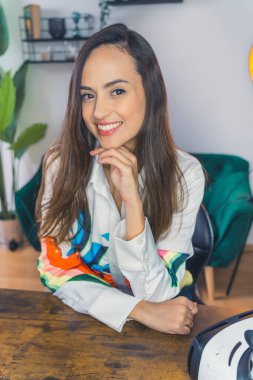 Smiling female podcaster sitting on a chair in her room before recording a podcast. High-quality photo