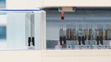 Laboratory automatic machine placing a blood sample on an empty holder, which is moving on on a conveyor belt. High quality 4k footage