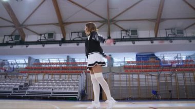 a cheerleader in white pantyhose and mini-skirt practicing in jumping before the game. High quality 4k footage