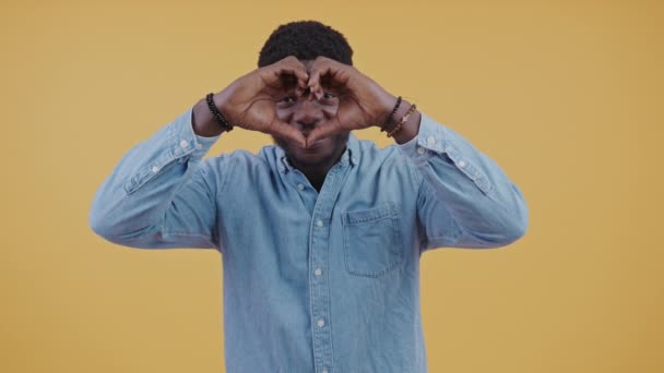 陽気黒い男は愛の概念にロマンチックな彼の指で心を作る 高品質4K映像 — ストック動画