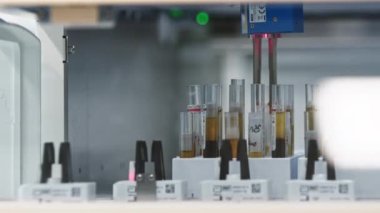 Otomatik makine test tüpü tutucusundan bir test tüpü alırken boş tutucular konveyör bandı üzerinde hareket ediyor. Yüksek kalite 4k görüntü