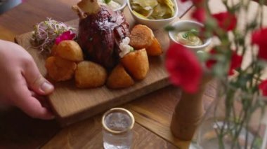 Hands putting baked pork knuckles or Golonka Polish cuisine on a wooden table. High-quality 4k footage