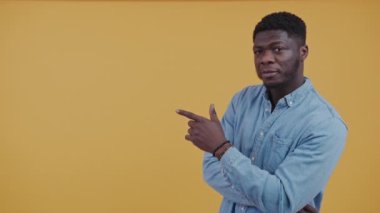 Afro-American man pointing towards his left for copy space isolated studio shot. High-quality 4k footage