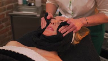 A woman having her face cleaned with a towel. Video. Beauty concept. High quality 4k footage