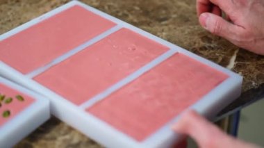 Close-up shot of plastic mold filled with pink melted chocolate tapped against table. Tempering chocolate. Chocolate production process. Horizontal indoor video. High quality 4k footage