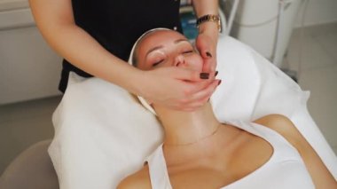 Attractive woman with eyes closed getting gentle face massage in a beauty clinic. High quality 4k footage