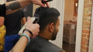 Yatay video. Saçını makasıyla kesen bir adam. Kuaför arka planda çalışıyor. Yüksek kalite 4k görüntü