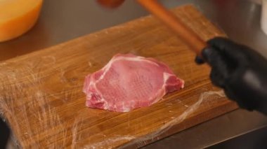 Şef, Schabowy Kotlet 'i hazırlarken domuz pirzolasına tahta tahtada et çekiciyle vuruyor. Geleneksel Polonya mutfağı. Yüksek kalite 4k görüntü