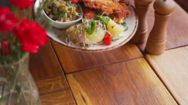 Şef geleneksel Polonya mutfağında kaynamış patates ve salata ile Schabowy Kotlet servis ediyor. Yüksek kalite 4K görüntü