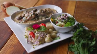 Domuz filetosu beyaz bir tepside servis edilir. Masada bolet sosu ve salata vardır. Yüksek kalite 4k görüntü