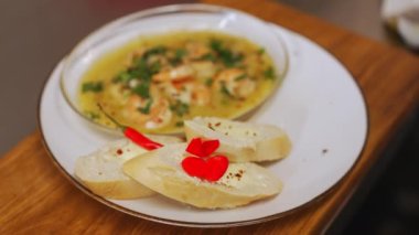 Şef sıcak soslu karides ve ahşap masada sarımsaklı ekmek ile taze salata ekler. Yüksek kalite 4k görüntü