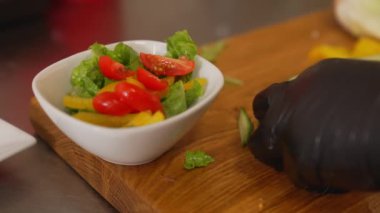 Şef salatalık şeritleri keser ve onları kiraz domatesli taze salata kasesine koyar. Yüksek kalite 4K görüntü