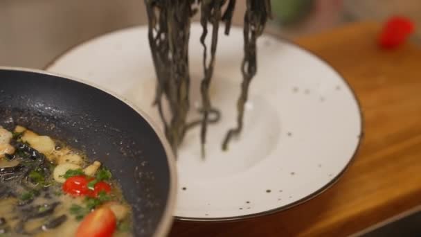 Šéfkuchař Připravuje Černé Taglioni Těstoviny Krevetami Pomocí Kleští Dřevěném Stole — Stock video