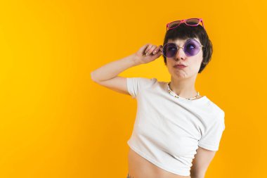 Beyaz bluzlu bir kadın, biri burnunda diğeri kafasının üstünde olmak üzere iki çift güneş gözlüğü takıyor. Yüksek kalite fotoğraf