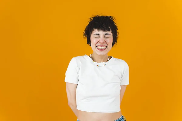 Woman grinning with her eyes closed. Orange background. Medium shot. Happiness concept. High quality photo