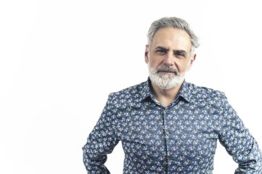 Stüdyoda, elleri belinde mavi desenli düğmeli gri saçlı yaşlı bir adamın fotoğrafı var. Gülümsüyor. Beyaz bir arka planda izole edilmiş. Yüksek kaliteli fotoğraf..