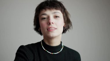 Gizemli olumlu genç kadın ellerini gri duvarın önünde kameraya doğru hareket ettiriyor. Yakın çekim stüdyo çekimi. Yüksek kalite 4k görüntü