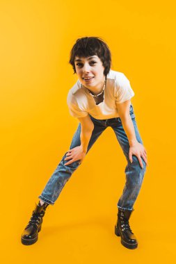 Dikey fotoğraf. Tam atış. Elleri dizlerinin üstüne çöküp kameraya bakan bir kadın. Yüksek kalite fotoğraf