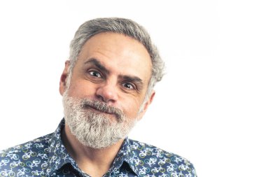 Mavi tişörtlü orta yaşlı sakallı bir adam yanaklarıyla komik bir surat yapıyor. Ağız havayla şişmiş. Beyaz arka planda izole edilmiş. Yüksek kaliteli fotoğraf.