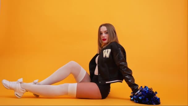 Ung Kvinna Cheerleader Sitter Golvet Orange Studio Bakgrund Högkvalitativ Film — Stockvideo