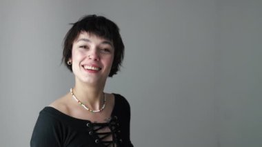 Tarz sahibi Gen Z iyimser kadın kameraya bakıyor ve gri arka planda gülümsüyor. Uzayı kopyala Gençliğin önemi. Yüksek kalite 4k görüntü