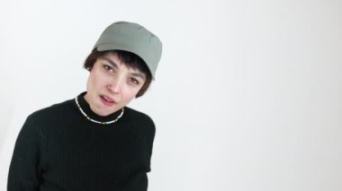 Kendine güvenen kız kameraya kızgın bakıyor ve beyaz arka planda bir göz kırpıyor. Uzay stüdyosunun fotoğrafını çek. Yüksek kalite 4k görüntü