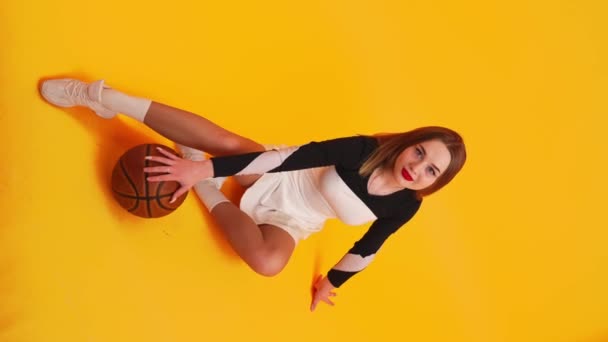Pełne Pionowe Ujęcie Młodej Charyzmatycznej Cheerleaderki Siedzącej Podłodze Pozującej Koszykówką — Wideo stockowe