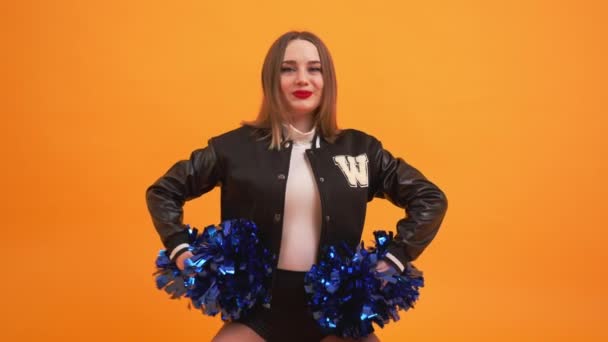 Cheerleaderka Wychowująca Niebieskie Pompony Pomarańczowym Tle Wysokiej Jakości Materiał — Wideo stockowe