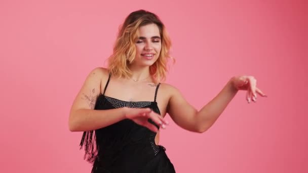 Mladá Žena Černých Lemovaných Šatech Tančí Rukama Izolovanýma Růžovém Pozadí — Stock video