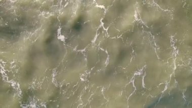Çamurlu deniz suyundaki dalgalar insansız hava aracı görüntüsünü alt üst ediyor. Yüksek kalite 4k görüntü