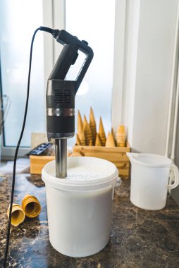 Mixing milk in a white container with professional blender for ice cream. High quality photo