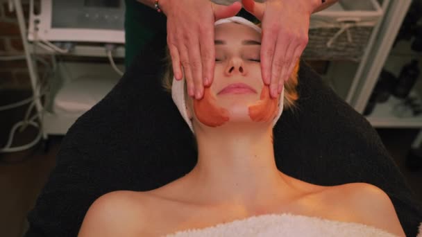 Kosmetikerin Die Eine Maske Aus Orangefarbenem Ton Aufträgt Indem Sie — Stockvideo