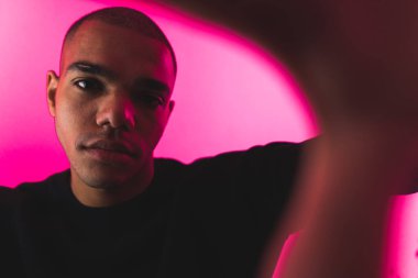 Odaklanmış adam modeli ellerini pembe arka planda kameraya doğru uzatıyor. Stüdyo çekimi. Yüksek kalite fotoğraf