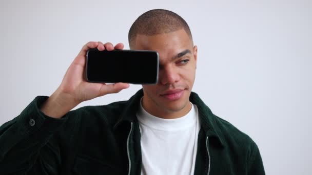 Positiv Leende Man Täcker Halva Ansiktet Med Mobiltelefon Och Tittar — Stockvideo