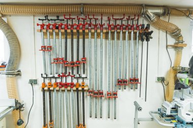 Marangoz atölyesinin duvarına dikey olarak kıskaçlar yerleştirilmiş. Ahşap işçiliği ve metal işçiliği. Yüksek kalite fotoğraf