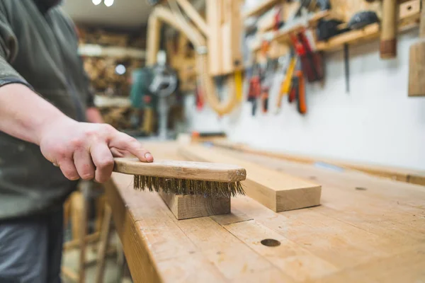 作業台の上に横たわる2本の木製の板の上に特殊な木製のブラシを使用して男性大工の手 大工に使われる道具 高品質の写真 — ストック写真