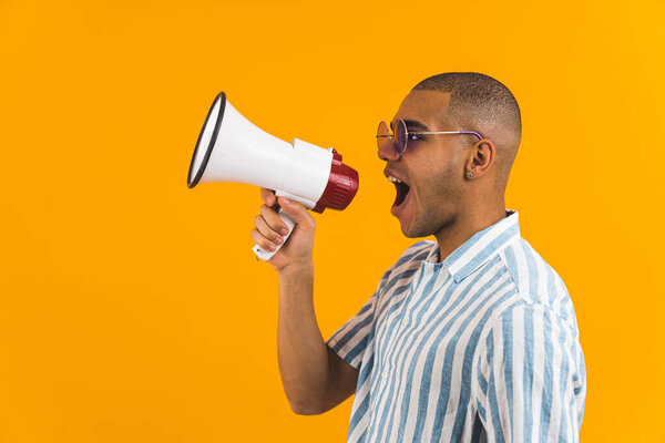 Вид сбоку на человека, кричащего в мегафон на оранжевом фоне. Высокое качество фото