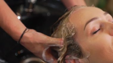 Güzellik salonunda nazikçe masaj yapan ve kadın müşteri saçlarını şampuanlayan kuaförün yakın parmakları. Yüksek kalite 4k görüntü