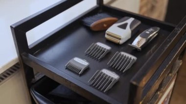 Modern elektrikli saç makasıyla bir set başlığı ve salonda siyah bir askıya yerleştirilmiş ahşap bir fırça. Yüksek kalite 4k görüntü