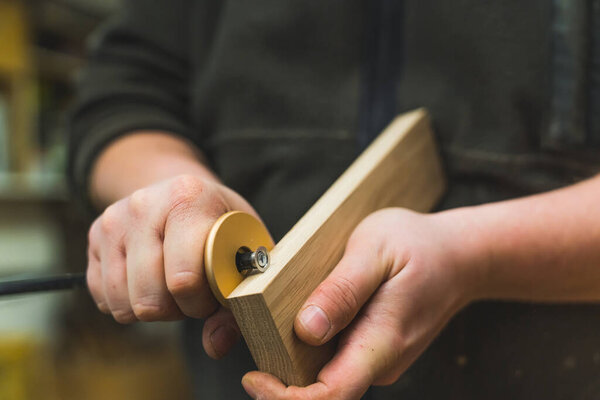 Closeup shot of adult caucasian male carpenter using marking gauge on wooden plank. Professional woodworking tool. High quality photo