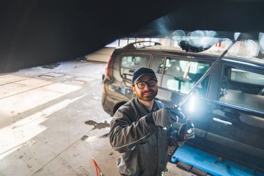 auto serviceman working on a car using special tools for chassis inspection, car workshop. High quality photo