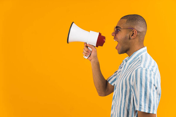 Профиль человека, кричащего в мегафоне на оранжевом фоне. Высокое качество фото