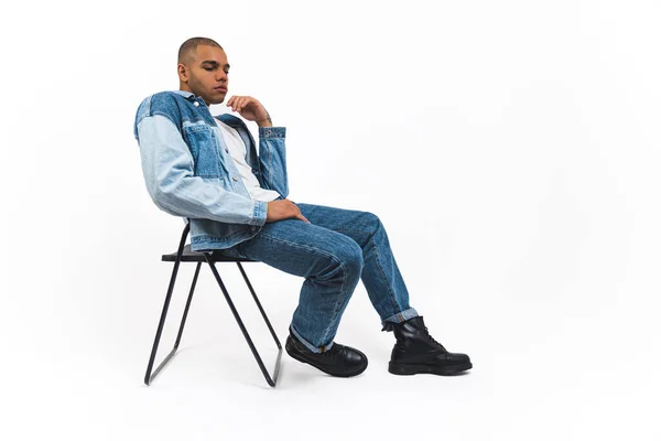 穿着全套斜纹棉布衣服的非裔美国男模坐在白色背景的折叠椅上 高质量的照片 — 图库照片