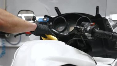 Beyaz bir motosikleti sarı bir süngerle temizlerken yakın çekim. Yüksek kalite 4k görüntü